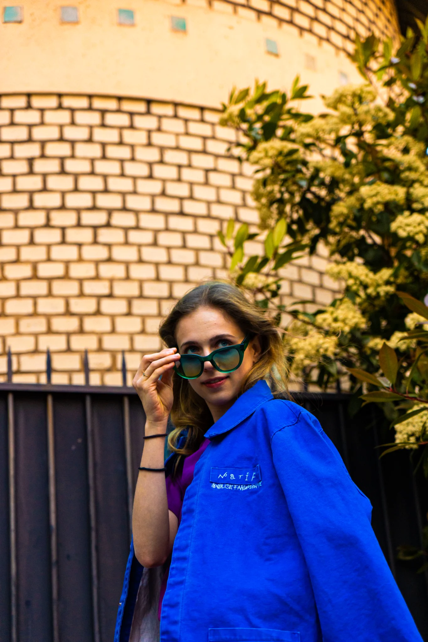 Portrait de mode portant une veste bleue Natif et des lunettes vertes